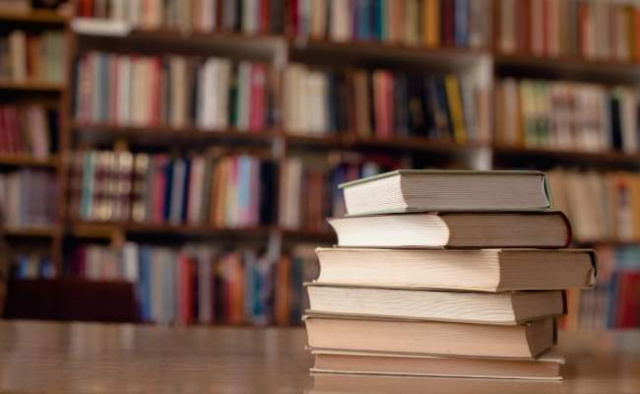 Stack of books on table with bookshelves in back of bookstore