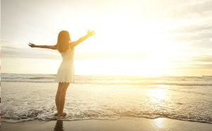 happy lady on beach with arms up in sky